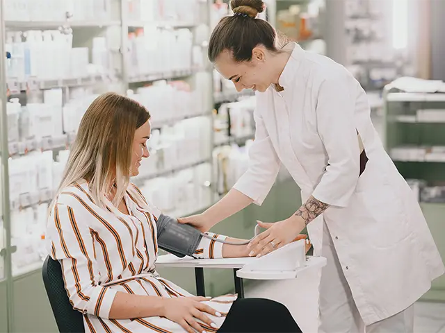 Pharmacist taking blood pressure of customer in the pharmacy