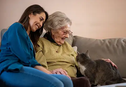 Grandmother and granddaughter petting a cat in a retirement home-long-term-care-category