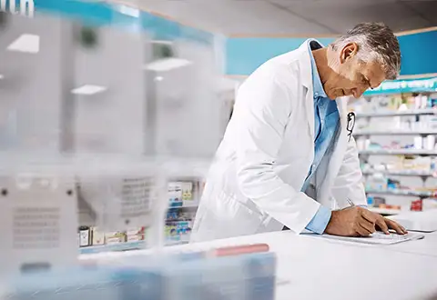 male-pharmacist-writing-on-a-clipboard-in-a-drugstore-business-operations-category