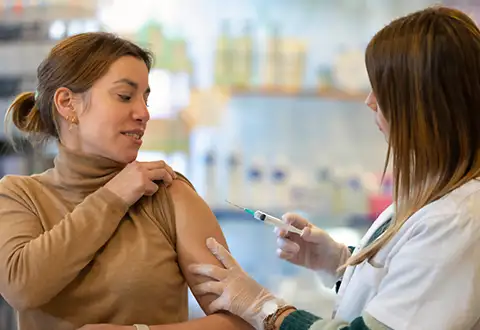 woman receiving a vaccine from pharmacist in pharmacy